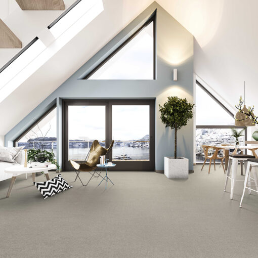 A Scandinavian-style loft interior with a high ceiling, a glazed, triangular far wall, and furnished with light coloured seating and a pale beige deep pile carpet